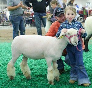 Girl smiling holding her sheep's leash